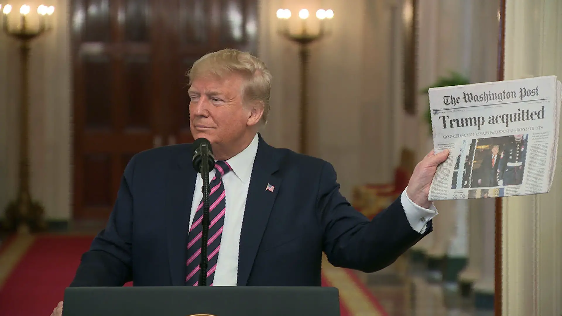 President Trump holds up newspaper with headline " Trump acquitted" 